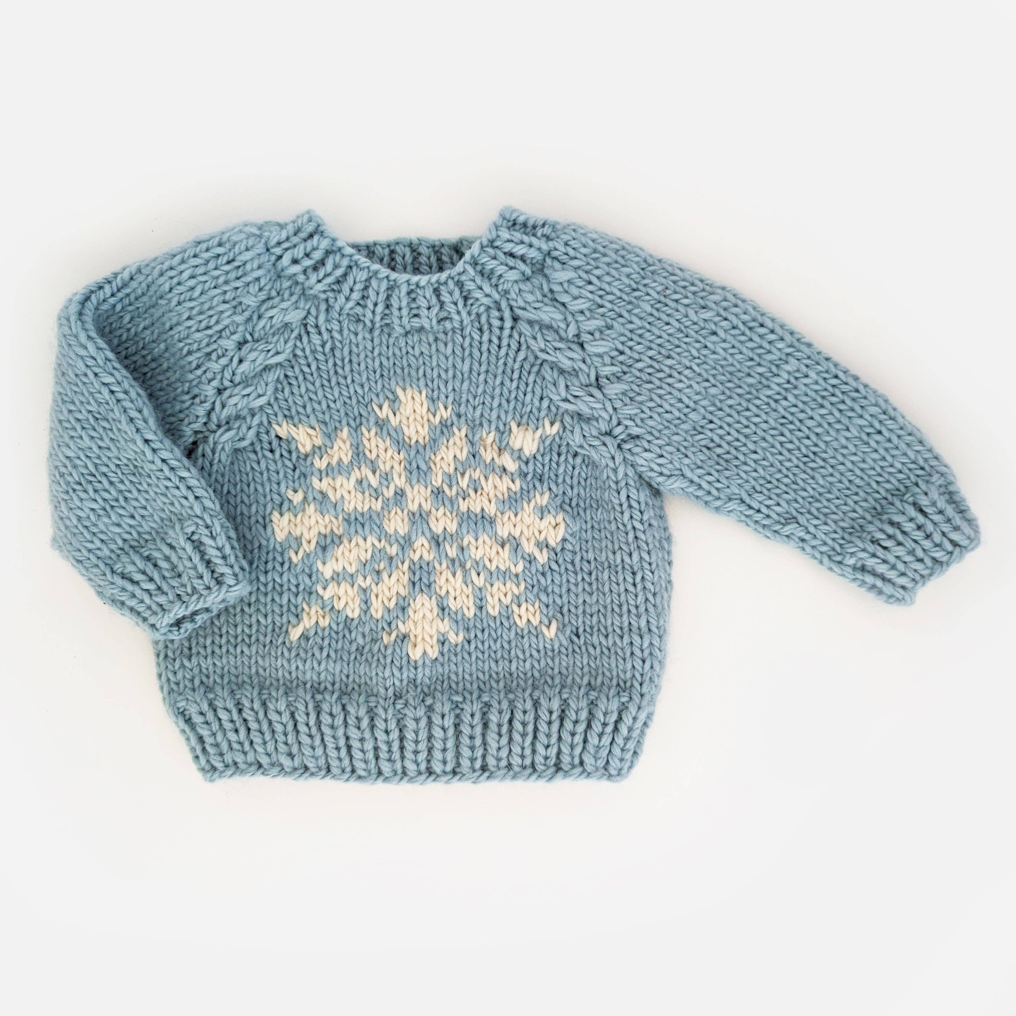 Blue knitted sweater with a snowflake pattern on a white background